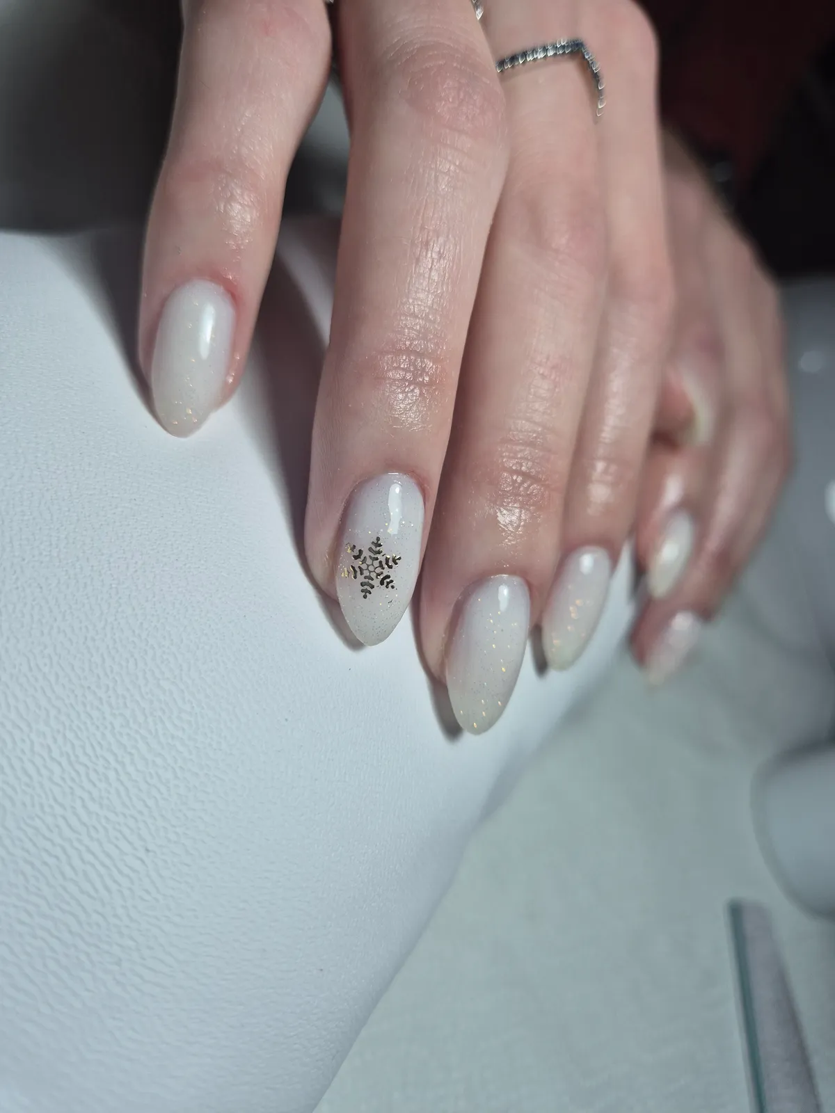 Milky white nails with a gold snowflake accent
