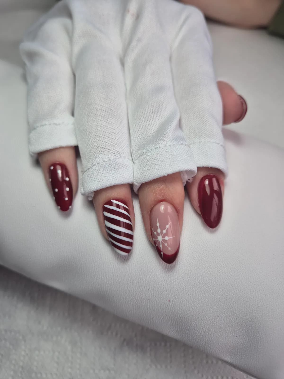 Cherry red nails with candy-cane stripes and a snowflake